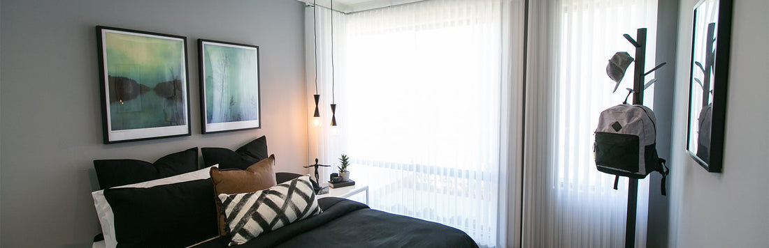 Modern bedroom featuring sheer curtains, stylish artwork, and minimalist decor.