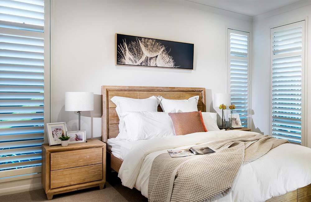 Cozy bedroom featuring wooden furniture and stylish window shutters allowing natural light.