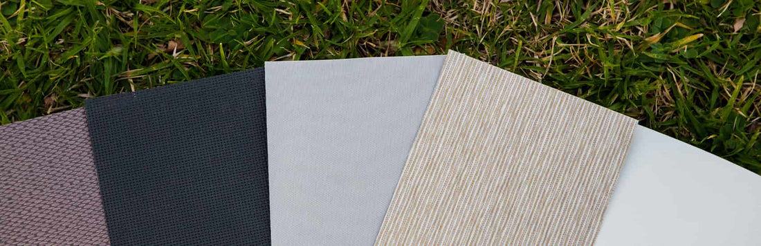 Different fabric swatches for blinds on green grass background, showcasing various colors and textures.