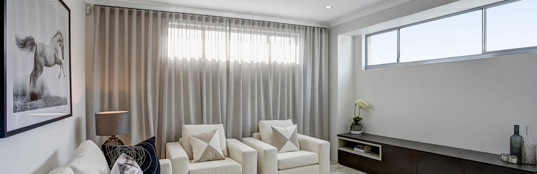 Bright living room featuring sheer curtains, two white armchairs, and modern decor elements.