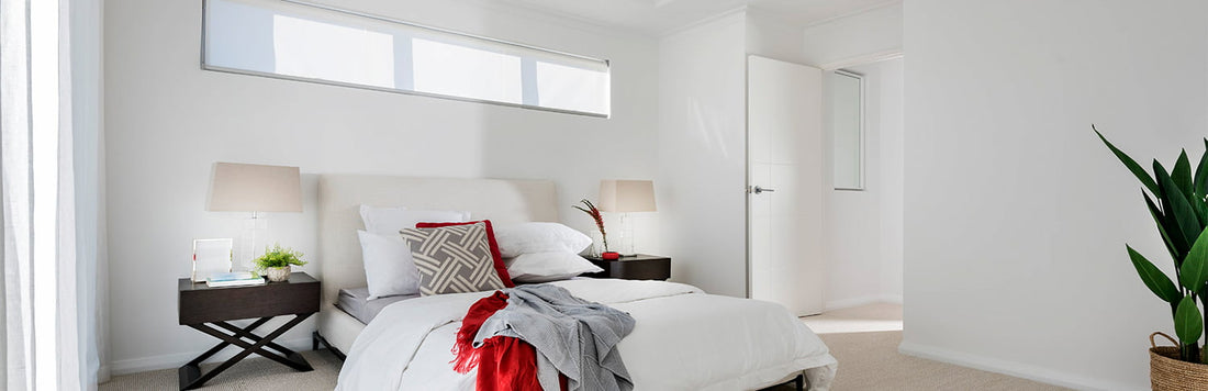 Minimalist bedroom with a large bed, bedside tables, and natural light from window.