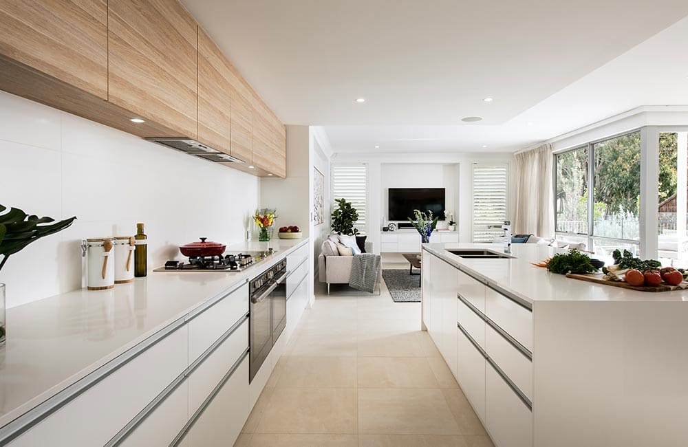 Modern kitchen with white cabinetry, wooden accents, and large windows showcasing natural light.