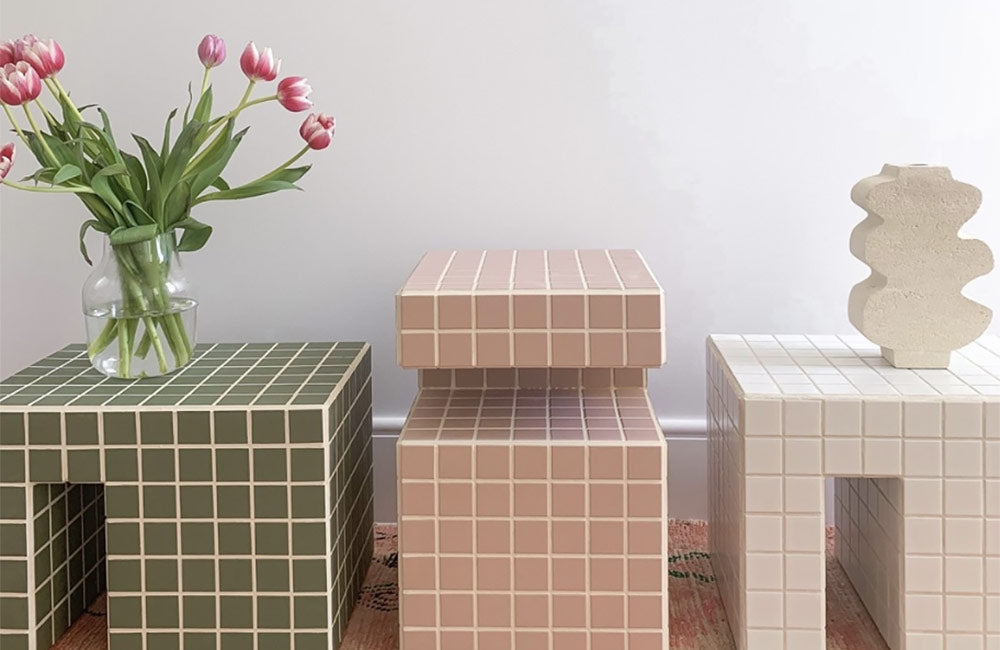 Stylish mosaic side tables in green, pink, and white with a vase of tulips, showcasing modern home decor trends.
