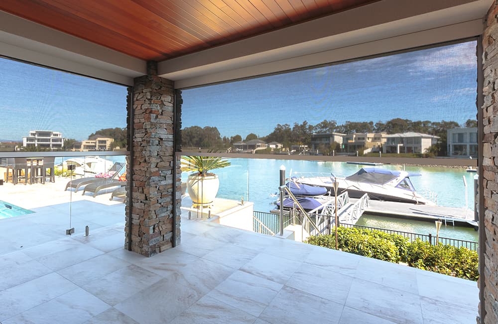 Spectacular view from a modern home overlooking a serene waterfront with boats and lush greenery.