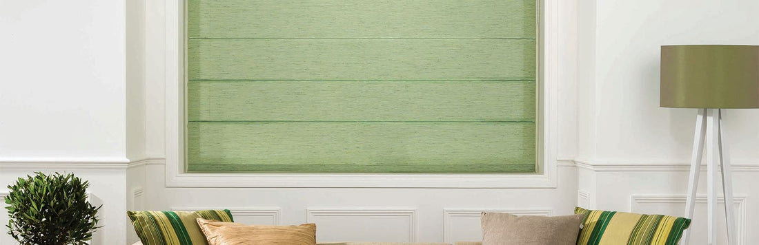 Green Roman blinds in a modern living room with decorative cushions and a stylish lamp.