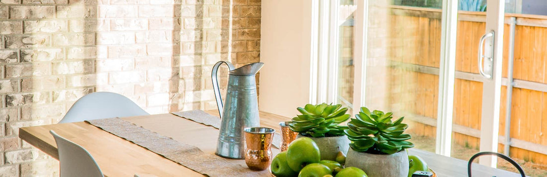 Bright kitchen scene with a wooden table, green apples, succulent plants, and a vintage pitcher.
