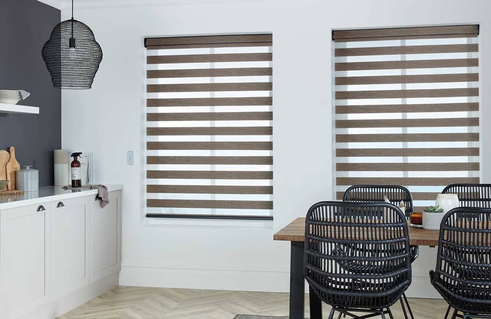 Modern kitchen with stylish curtain roller blinds and black dining chairs creating a cozy dining atmosphere.
