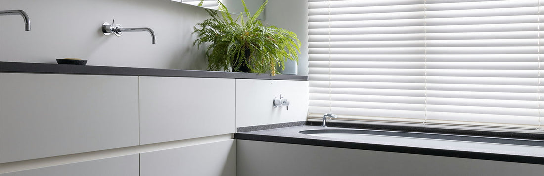 Modern bathroom design featuring white blinds, sleek cabinetry, and a potted plant.