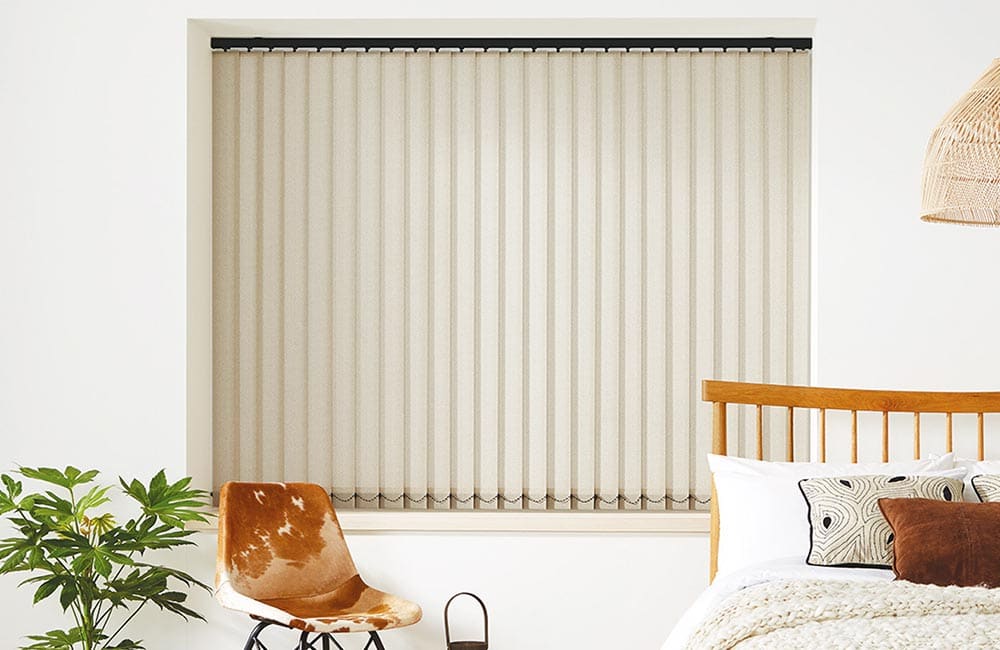 Modern beige vertical blinds installed in a bright bedroom, enhancing privacy and style.