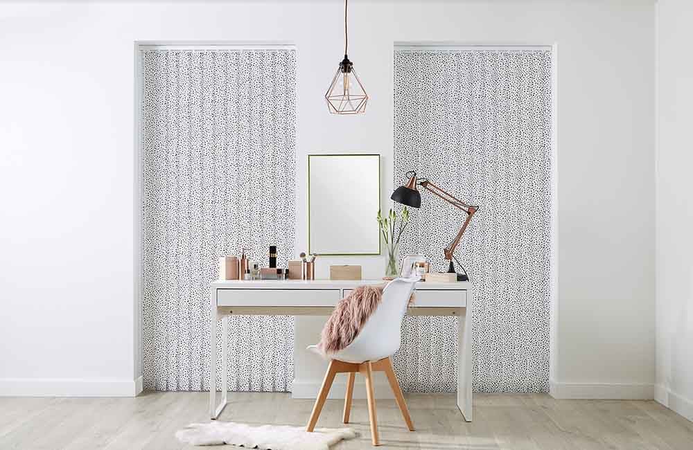 Stylish home office featuring patterned blinds, a modern desk, and decorative elements for an organized workspace.