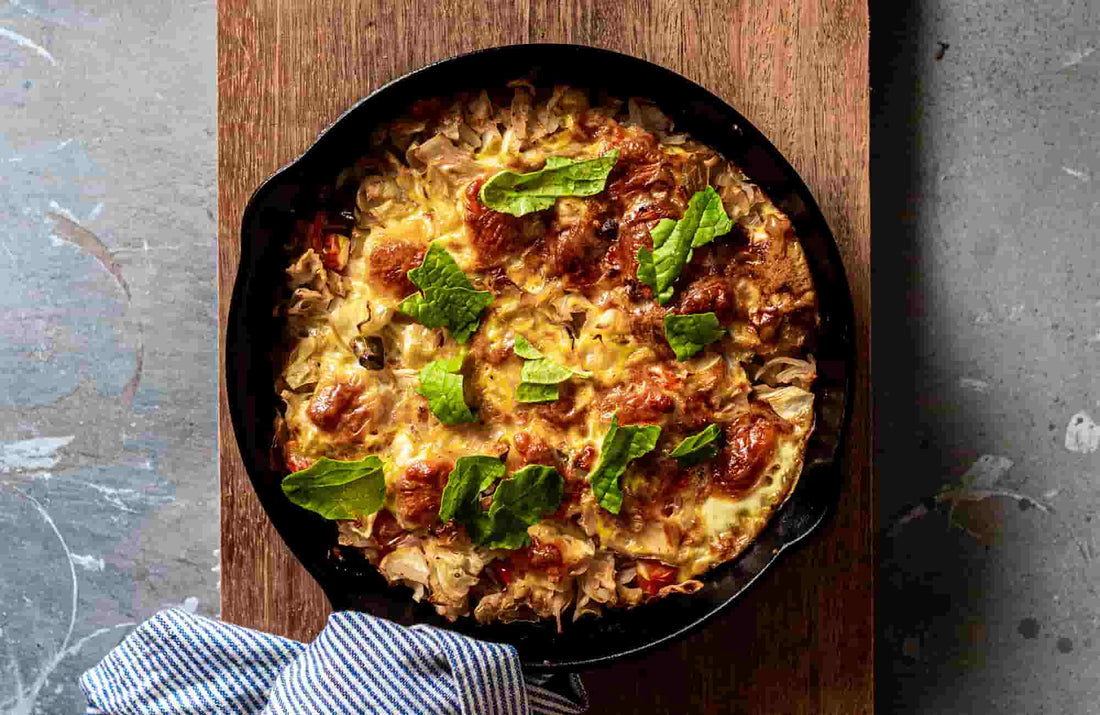 Delicious spring frittata topped with fresh herbs in a cast iron skillet, served on a wooden board.