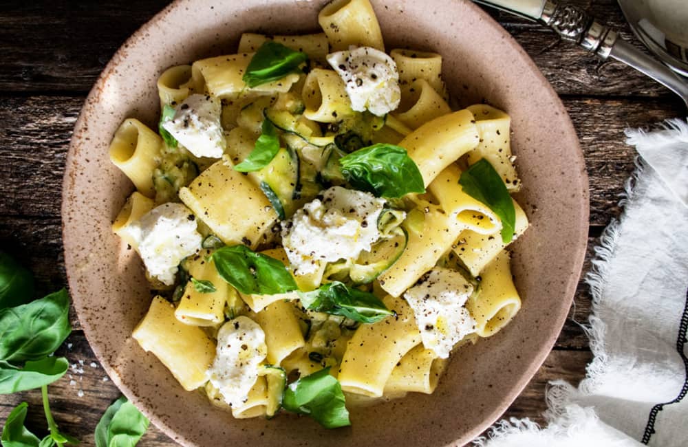 Delicious summer pasta dish with zucchini, ricotta, and fresh basil served in a rustic bowl.